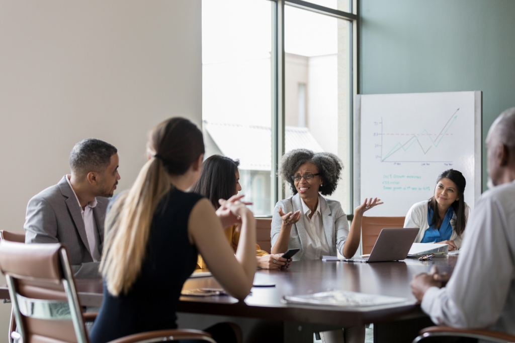 Employees gathered around a work table for year-end board meeting